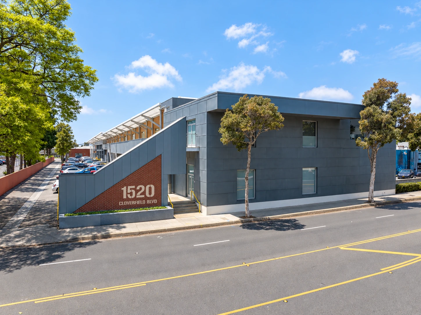 1520 Cloverfield Creative, showing the gray street facade, brick 1520 entrance and open-air gallery